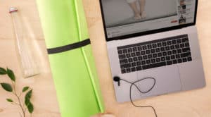 Virtual yoga class with green yoga mat and open laptop