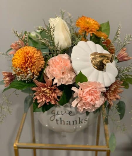 Designed in a white ceramic pumpkin, this arrangement is a perfect fall gift. Warm hues of pumpkin spice will certainly delight the recipient. 